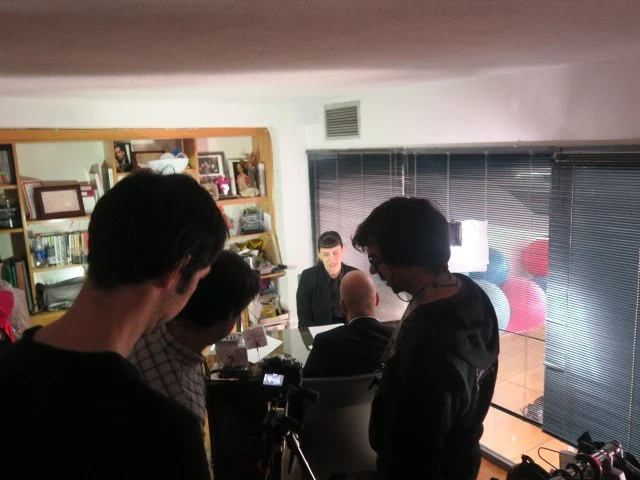 Small film crew working behind the camera on an indoor set